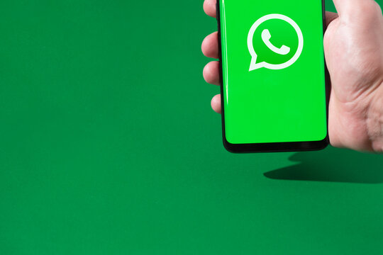 Person holding a smartphone with the WhatsApp logo on the screen.