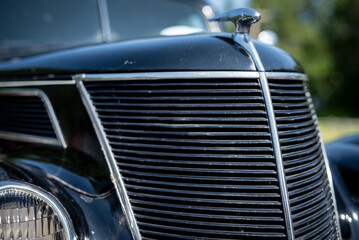 Closeup of the grille of a restored antique automobile, with selective focus and shallow depth of field.