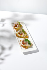 Aesthetic composition with tomato bruschetta on white background with harsh shadows. Italian bruschetta with tomatoes and cheese on fine dining in summer. Elegant menu concept.