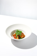 Crispy eggplant in chinese style on white plate. Crispy eggplant salad on summer menu. Asian appetizer - roasted aubergine with coriander leaves. Vegan food. Aesthetic veggie menu.