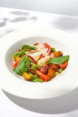 Salad with octopus, baked potatoes and poached egg on white table with hard shadows. Seafood salad with vegetables and potatoes in summer menu restaurant. Octopus and eggs salad in modern style.