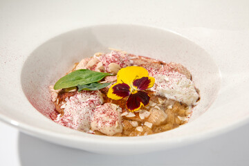 Creative creamy risotto with eel and cheese espuma. Fish risotto on white plate with unagi sauce and eel in summer menu Italian risotto from chef with smoked eel and spinach with shadows of leaves