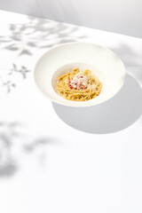 Spaghetti with crab meat and cheese on white table with shadows. Seafood pasta with spaghetti and crab in summer italian menu Italian pasta with parmigiano cheese and crab meat