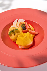 Yellow mousse cake in contemporary style on white background. Passion fruit cake with mango mousse and berries. Yoghurt cake with passion fruit on restaurant plate Light mousse dessert