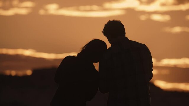 Slow motion silhouette of couple with cell phone photographing dramatic sky / Boulder, Utah, United States