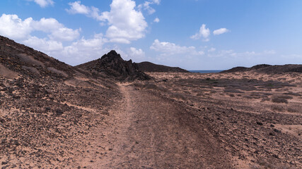 Dark desert surface with some volcanic hills across Lobos Island, Spain