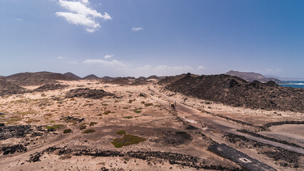 Volcanic hills surrounded by light colored sands with small road across Lobos Island, Spain