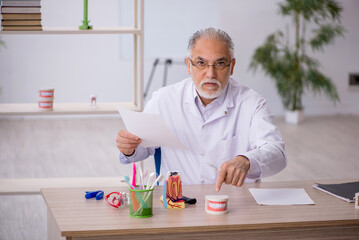 Old male dentist working in the clinic