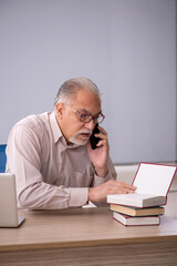 Old male teacher in front of whiteboard