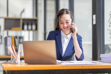 Shot of a asian young business Female working on laptop computer in her workstation.Portrait of Business people employee freelance online marketing Call phone e-commerce telemarketing concept.