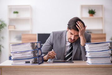 Young male employee unhappy with excessive work in the office