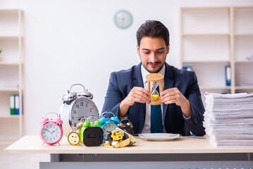 Young businessman employee eating alarm-clock