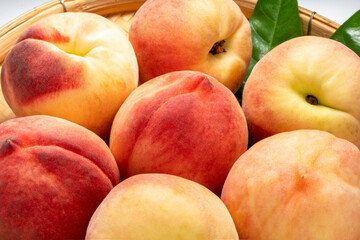 Fresh Sweet Peach on pink wooden  basket, Pink and yellow Peach fruit with leaf on bamboo basket isolate on white.