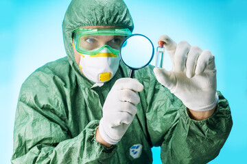Biotechnology lab. scientist in protective clothing examining examines a test tube with liquid,...
