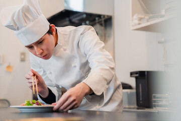 料理の盛り付けをする男性シェフ