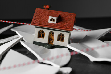 House model and broken dishes on black table depicting destruction after earthquake