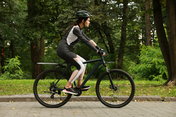 Fototapeta na wymiar Young woman riding bicycle on road outdoors