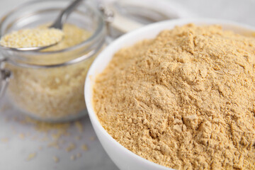 Sesame flour in ceramic bowl on white table, closeup