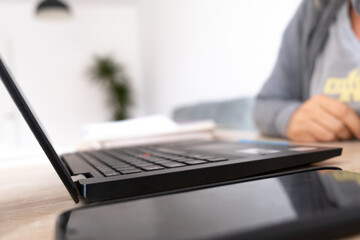 closeup of computer, smartphone and, blurred background woman working from home
