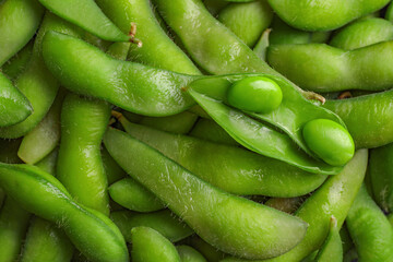 Many green edamame beans in pods as background, closeup