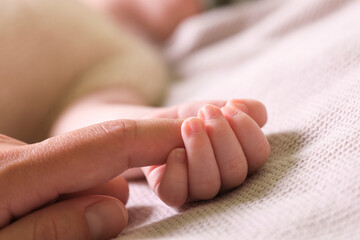 Mother and her newborn baby on light grey knitted plaid, closeup
