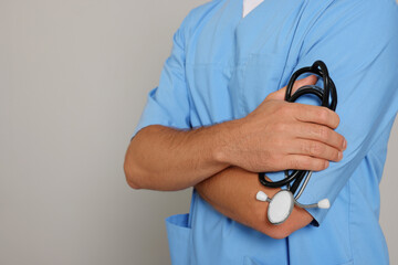 Doctor with stethoscope on light grey background, closeup