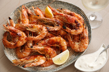 Plate of delicious cooked shrimps served with lemon, sauce and wine at table, closeup