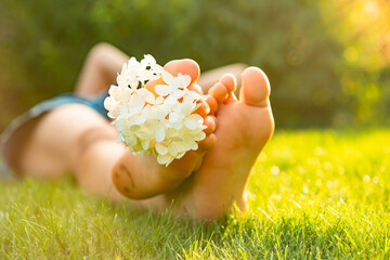 Teenage girl with beautiful hortensia flowers lying on green grass outdoors, closeup