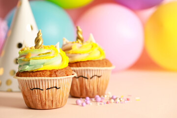 Cute sweet unicorn cupcakes on beige table, space for text
