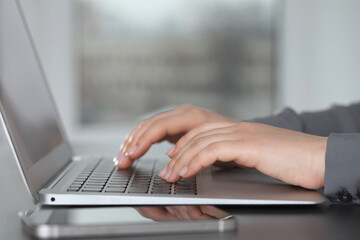 Woman typing on laptop at table, closeup. Electronic document management