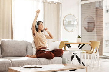 Music, laptop and woman dance on sofa streaming audio podcast, radio sound or digital online playlist. Work from home, wellness and relax designer listening to download song on fun break