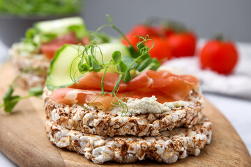 Crunchy buckwheat cakes with cream cheese, prosciutto and cucumber slice on wooden board, closeup