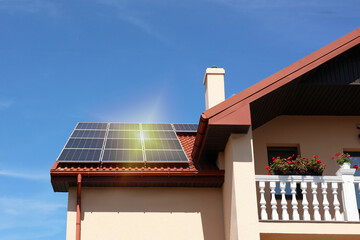 House with installed solar panels on roof under blue sky. Alternative energy source © New Africa