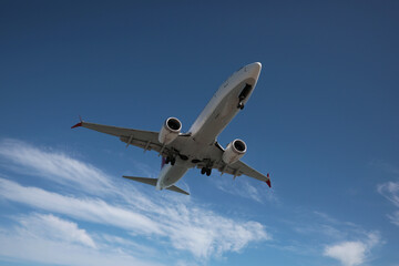 Fototapeta na wymiar Modern white airplane flying in cloudy sky, low angle view