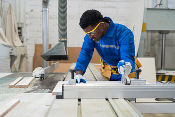 African American male carpenter worker working with saw machine at wood workshop. Male joiner worker in safety uniform and equipment tools working in wood factory. Manufacturer industry manufacturing - Powered by Adobe