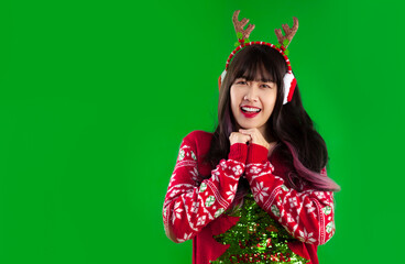 Young asian woman long hairstyle in red white and green color christmas theme sweater posing make a wish on green screen background.