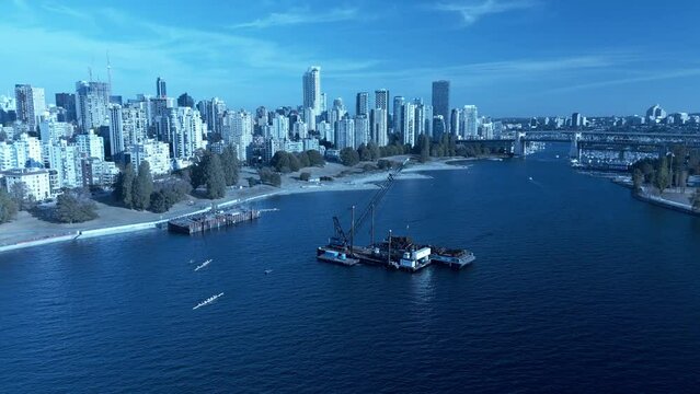 barge adrift at Vancouvers sunset beach while contractors dismantle wreckage as its a normal day for rowing team training baoting thru and in between vessels on a bright sunny day in BC 4k barge2-3