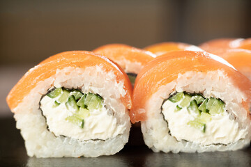 Traditional sushi roll Philadelphia set on a black background with reflection, close up. Sushi roll with rice, cream cheese, salmon. Sushi menu. Japanese kitchen, restaurant