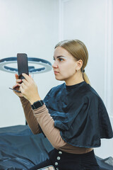 A woman permanent makeup artist draws a sketch of the eyebrows on the face of her client.
