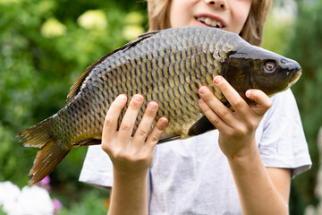 big fish carp in the hands of a boy, fishing with a child, a young fisherman