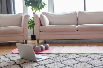 Dumbbells, sports mat and laptop at home with copy space