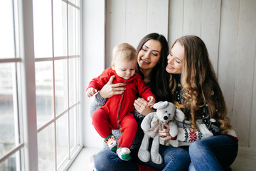 Happy smiling family at  studio on background of the Christmas tree with gift