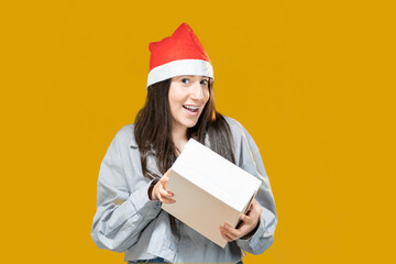Regalo a sorpresa per Capodanno o Natale. Sorridente ragazza isolata con sfondo giallo 