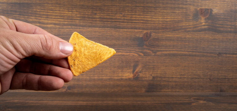 Corn Chips Nachos In The Man's Hand.  Wood Texture Background