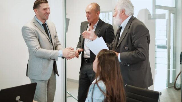 Old boss and colleagues congratulate successful best male employee who gets promotion reward 