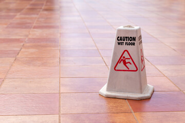 A plastic cone placed on the floor with the message Caution slippery floor.