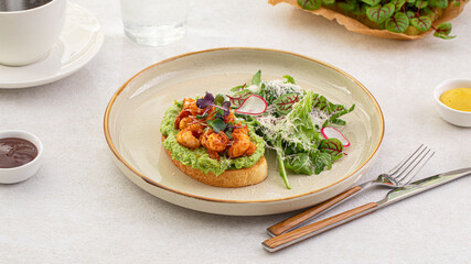 Portion of avocado toast with grilled shrimp and salad