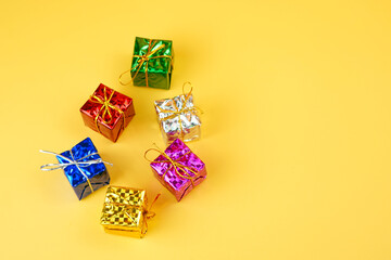 Metallic colorful presents with gold strings isolated on yellow