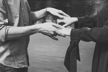 Close up partners holding hands monochrome concept photo. Romantic couple. Side view photography with lake on background. High quality picture for wallpaper, travel blog, magazine, article