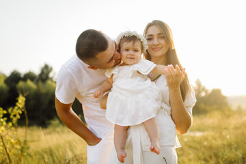 Fototapeta premium Young family with cute little daughter walking in forest on the sunset